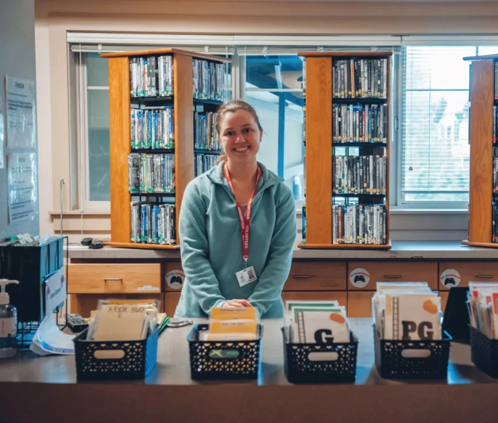 adult female volunteer smiling behind reception desk