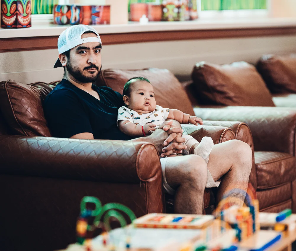 father sitting on couch with young child in his lap
